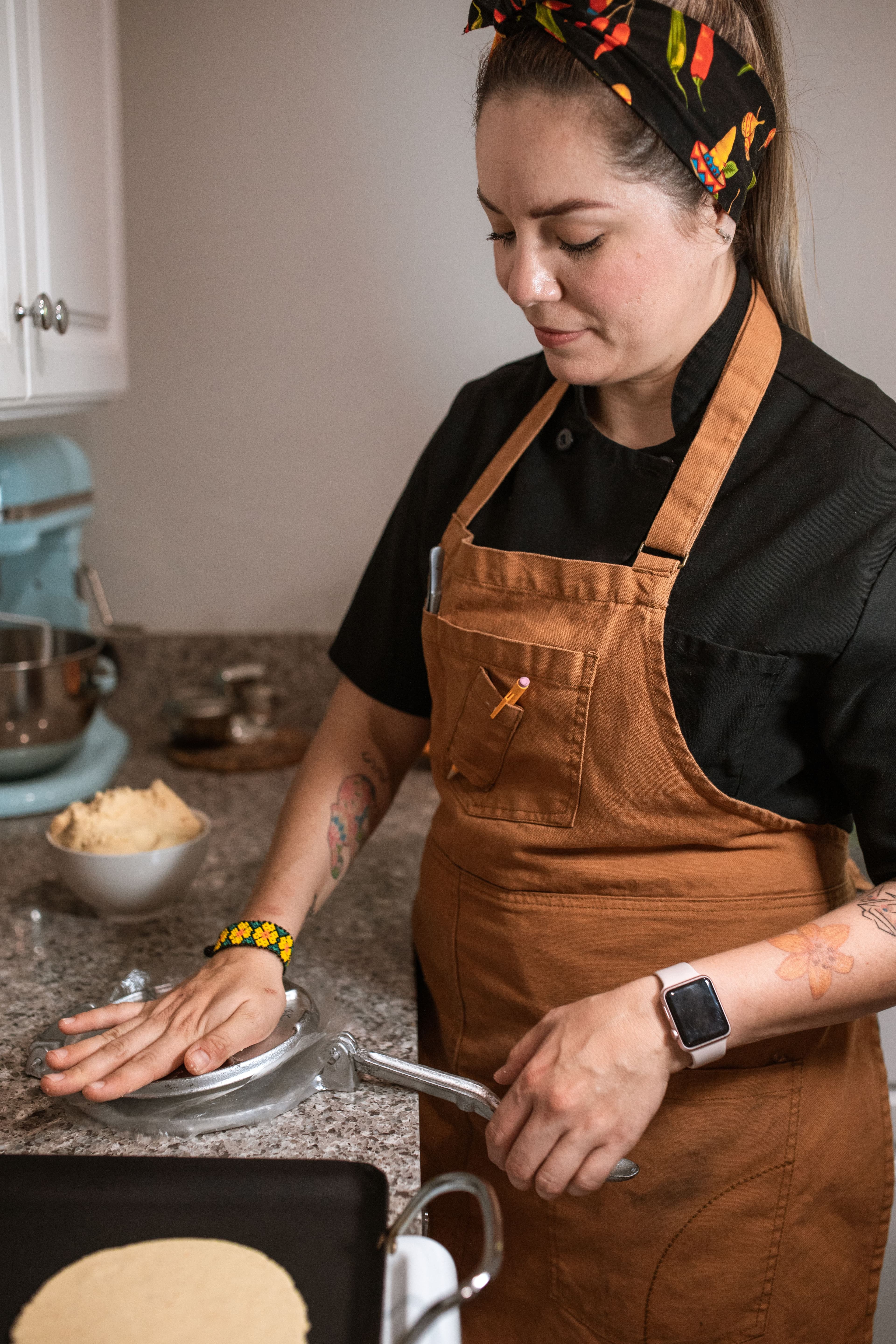 A cook pressing fresh tortillas at the griddle