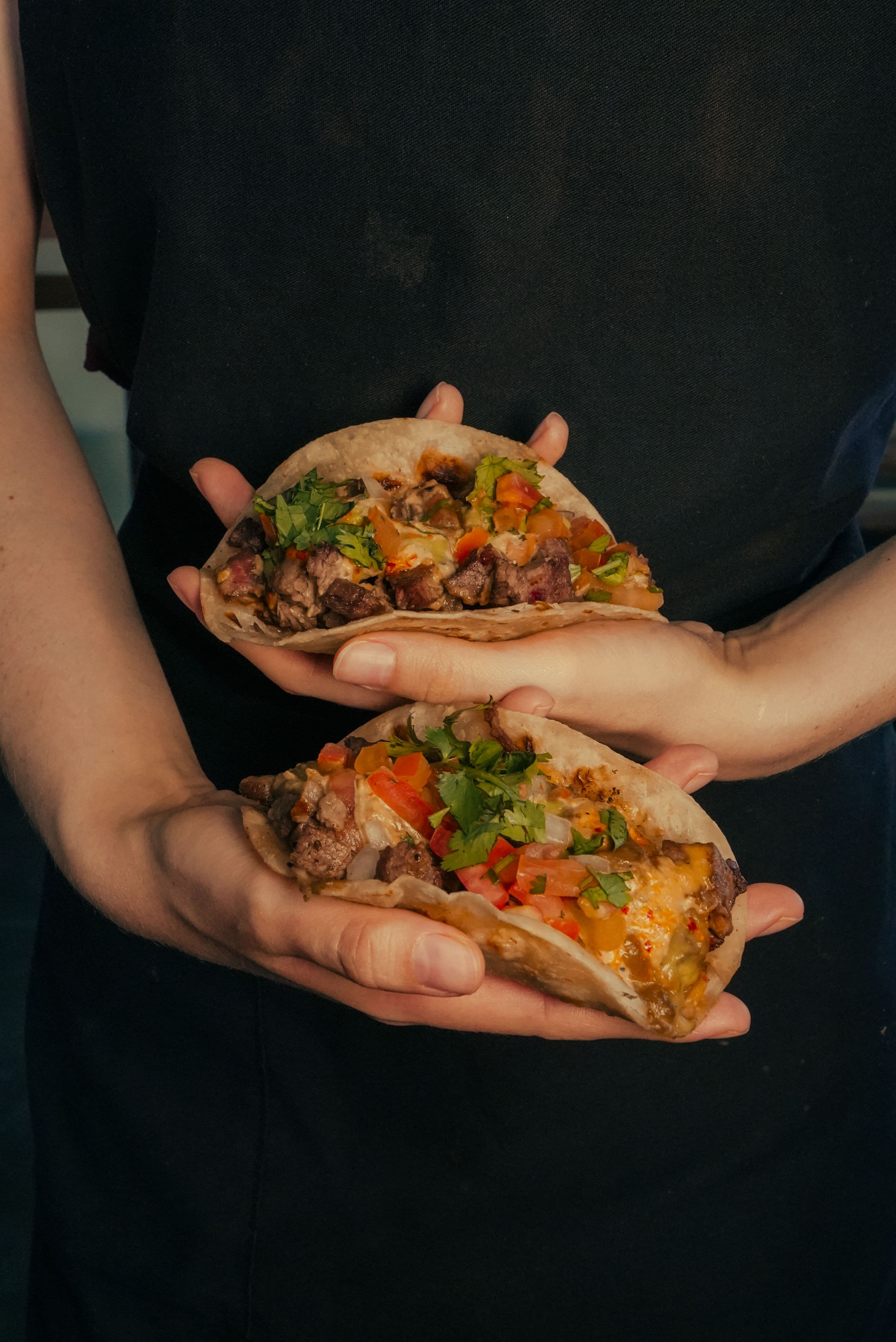 Tacos al pastor sizzling on a hot comal with charred onions